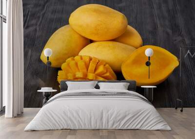 Four whole mango fruits on wooden table and cut into slices. Large juicy bright ripe yellow fruits Wall mural