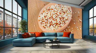 heap of quinoa in wooden spoon on wooden background, side view Wall mural