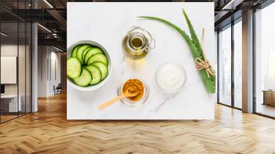 Homemade skin care concept. Green natural ingredients aloe vera, lemon, yogurt, turmeric, cucumber for making a cosmetic mask on a light background. Wall mural