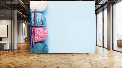 Multicolored crochet hooks with balls of yarn on a blue background with copy space. Wall mural