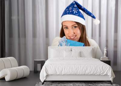 The girl is smiling, holding a Packed Christmas gift in front of her. Selective focus. Wall mural