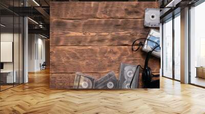 Portable retro stereo cassette player, old headphones and cassettes ont he brown wooden table background. Wall mural