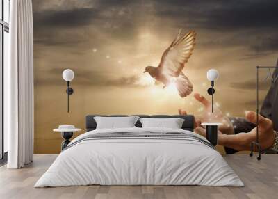 Businessman release dove from their hands flying against the background of a sunny sunset. Wall mural