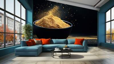 A close-up image of a black bowl filled with vibrant yellow culinary powder or spice, with particles freshly sprinkled around, set against a dark background. Wall mural