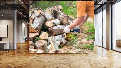 A man chops wood with a large ax in the yard of his house. Procurement of fuel for the winter for heating housing. Selective focus Wall mural