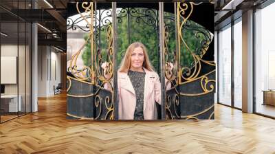 A mature blonde woman opens forged doors. New life Wall mural