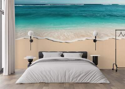 A scenic view of a sandy beach with gentle ocean waves rolling onto the shore under a clear blue sky. Wall mural