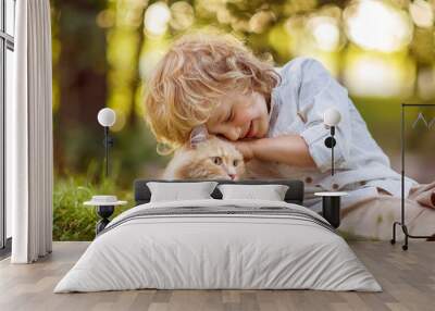 Little curly boy with a redhead cat, outdoor Wall mural