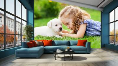 Little curly girl with a labrador puppy, outdoor summer Wall mural