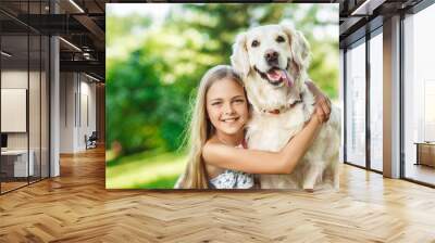 Little girl sitting on the grass with golden retriever dog in the summer park Wall mural