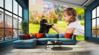 Little girl with a berner sennenhund puppy, outdoor, summer Wall mural