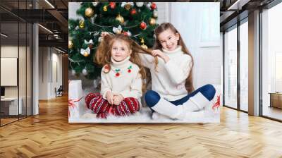 Two little girls near the Christmas tree with gifts Wall mural