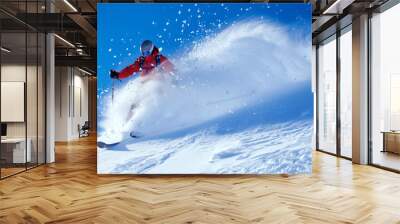 Dynamic image of a skier in a red jacket swiftly descending a snow-covered slope, creating a spray of snow. Wall mural