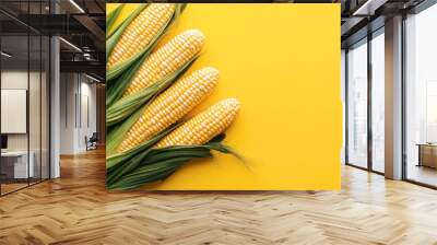 Four cobs of fresh corn with green husks displayed against a vibrant yellow background. Wall mural