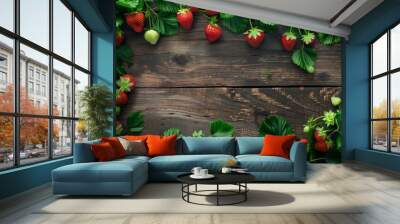 Fresh ripe strawberries with leaves spread on a rustic wooden background, creating a natural frame. Wall mural