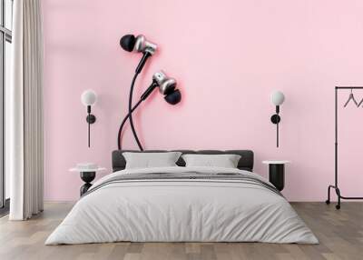 A pair of black music earphones for smartphone on a pastel pink background. Minimalist flat lay. Place for writing. Copy space. Wall mural