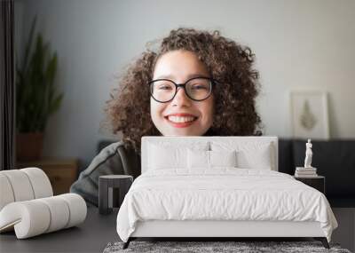 girl looks at camera and smiles. student talks over Internet. Video Conference or e-learning at home. portrait of teen at wide angle. Wall mural