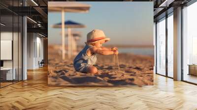 kid in a hat playing with sand on the beach by the sea. holidays with children near the ocean Wall mural