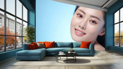 Beautiful young asian woman with clean fresh skin on blue background, Wall mural