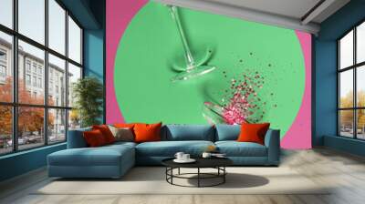 Two champagne glasses with splash of confetti over creative background Wall mural