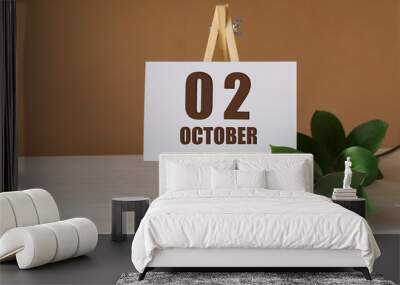 October 2th. Day 2 of month, Calendar date. Green branch, easel with the date and month on desktop. Close-up, brown background. Autumn month, day of year concept Wall mural