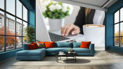 Professional businesswoman working on a laptop in a modern office with coffee and organized documents Wall mural