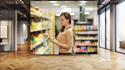 Woman who chooses products in the supermarket. Read product information.Concept of healthy food, bio, vegetarian, diet. Wall mural