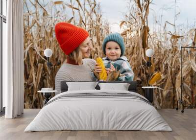 Mother and son exploring corn harvest in background of an agricultural field area. Wall mural