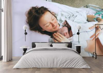 Mother holding her newborn baby after labor in a hospital. Wall mural