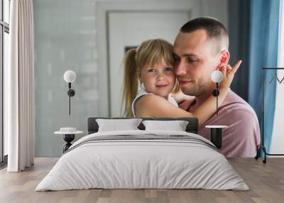 Blonde daughter hugs dad tightly at home in room Wall mural