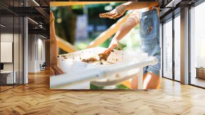 Happy children play with sand and water in sensory baskets on the outdoor sensory table, sensory early development, montessori. Baby hands with sand and water close up, soft focus Wall mural