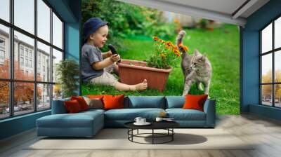 Little boy gardening and planting flower in garden Wall mural