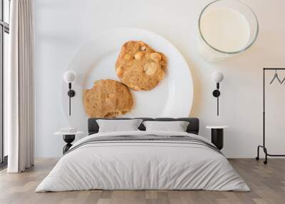 High angle view of homemade cookies with bite taken out on plate with glass of milk against white background Wall mural