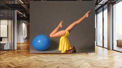 A girl in a yellow dress in the gym is engaged in gymnastics Wall mural