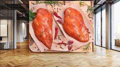 Marinated Chicken Breast with spices rosemary and vegetables on a cutting board and on a wooden table. Top view. Chicken meat closeup. Raw meat in marinade. Tasting diet meat. Wall mural