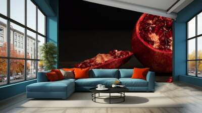 
pomegranate fruit. cut tropical red fruit on a black background. pomegranate seeds Wall mural