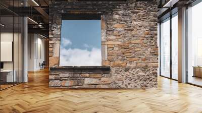 Window in ancient stone wall of damaged house, toned. Abandoned medieval building, filtered. Blue sky in window of ruin temple. Destroyed facade of old stone building. History concept.  Wall mural