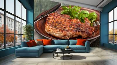 a piece of fried pork with herbs on a white dish on a wooden table, closeup view Wall mural