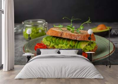 Vegan sandwich with avocado and tomatoes on a plate, on a gray background Wall mural