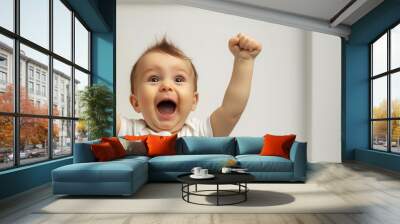 A baby is smiling and holding up his arms in the air. baby is happy and excited. A cute baby's delighted expression against a white backdrop, capturing the joy of discovery Wall mural