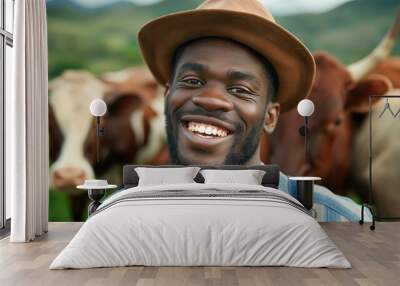 A man with a brown hat and a smile is standing in front of cows. The cows are in the background. Happy black man, tablet and animals in agriculture, farming or sustainability in the countryside. Wall mural