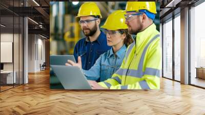 Three people wearing safety gear are looking at a laptop computer. They are likely discussing work-related information or a project Wall mural