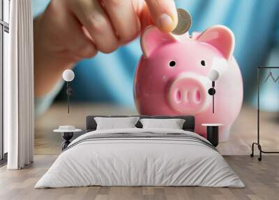 Man putting a coin into a pink piggy bank concept for savings and finance Wall mural