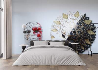 Two decorative masks from plaster close up on the white isolated background. One black-and-white with a crown on the head. Another is less red-white. Ornament in an interior. Festive mood. Horizontal  Wall mural