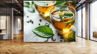 Cup of hot  black tea and green leaves. Wall mural