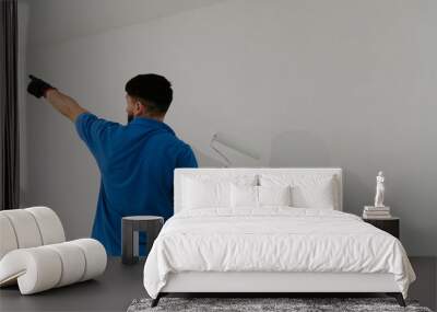 A young oriental man paints a wall with a roller. Wall mural