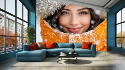 Fashionable woman in orange parka with fur hood looking at camera in winter outdoor setting Wall mural