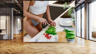 Sexy housewife dressed in lingerie preparing a vegetable salad while standing at the kitchen counter. Healthy lifestyle concept Wall mural