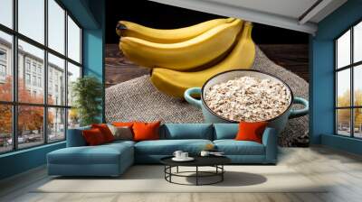 Banana and oat flakes on dark wooden background. Wall mural