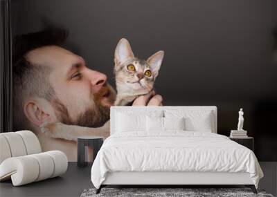 close up of bearded man holding his grey cat at home. cute abyssinian kitten of blue color with ambe Wall mural